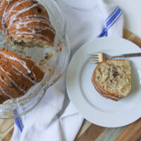 Banana Coffee Cake on a cake plate with a cut slice on a plate