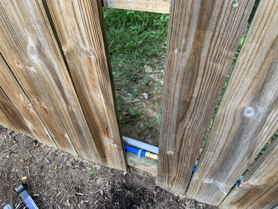 irrigation tubing running behind privacy fence
